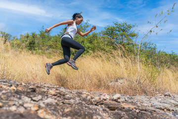 female trail runner jumping on running on trail on mountain in summer