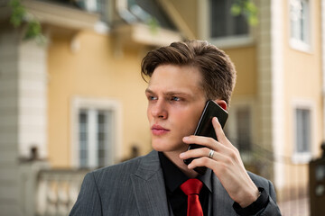 Handsome teenager in suit talking on phone, closeup 
