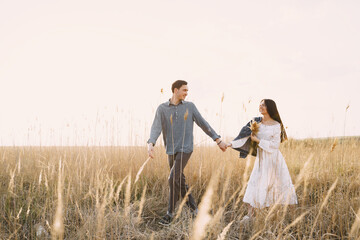 Happy couple in love in wheat field at sunset