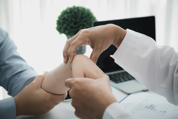 Orthopaedic doctor doing physical examination patient with wrist pain at the clinic. Physical...