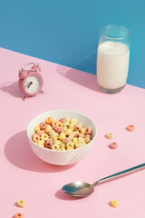 Colored grain rings in a white bowl on pink table. Childrens breakfast food
