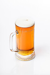 Mug of cold light beer on a white background. Beer foam and bubbles. Vertical shot. Traditional light alcoholic drink shot. Close-up. Copy space