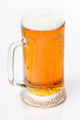 Close-up mug of cold light beer on a white background. Beer foam and bubbles. Vertical shot. Traditional light alcoholic drink shot.