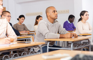 Portrait of attentive focused Latino on lesson in school auditorium. Adult learning and education...