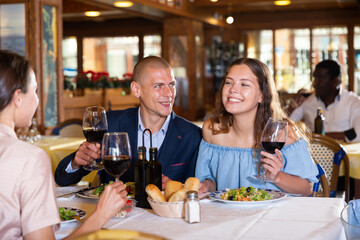 Young adult people enjoying food and having friendly conversation at restaurant