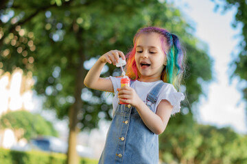 caucasian little girl is blowing a soap bubbles in park. Image with selective focus