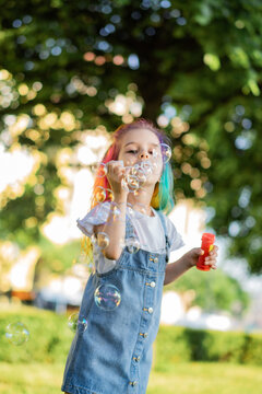 caucasian little girl is blowing a soap bubbles in park. Image with selective focus