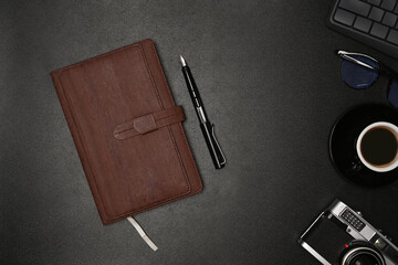 Notebook, pen and camera on black leather.