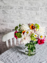Bright bouquet of summer flowers in a glass vase on a table in a bright room. Home interior