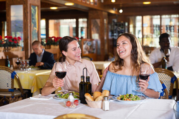 Women lesbian lgbt couple enjoying dinner with wine and having conversation at restaurant