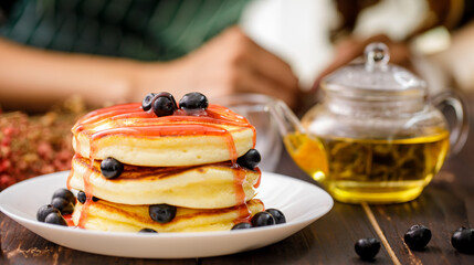 Sweet food. Stack of delicious pancakes topped strawberry jam.with blueberries and  teapot in white plate on blur background.