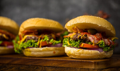 Three hamburgers with beef burger cutlet, fried onion, spinach, ketchup sauce and cheese, served on...