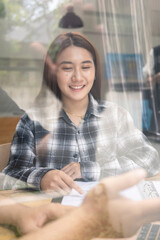 View through glass wall of smiling woman working in coffee shop.