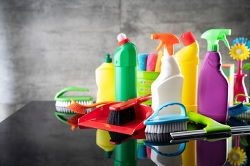 Summer house and office cleaning. Colorful set of bottles with clining liquids and colorful cleaning kit on the gray tiles background.