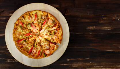 Background, banner and Close up on decorated homemade seafood pizza with shrimp, crab sticks, bell peppers topping on wooden tray