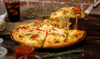 Selective focus and close up on a piece of double cheese homemade seafood pizza on spatula or scoop...