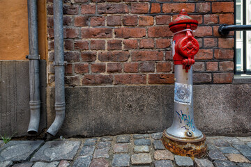 Vintage, red metal fire hydrant against an old brick wall. Copenhagen - Denmark