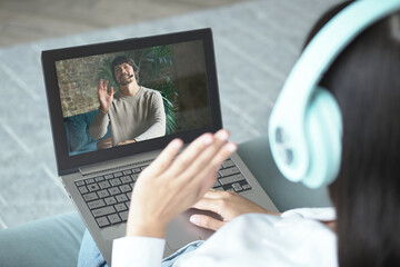 Young woman in headphones using laptop for video call.