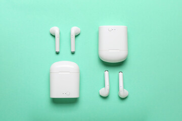 Modern earphones with cases on color background