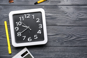 Composition with stylish clock and stationery on dark wooden background