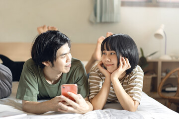 Young adult asian lover couple together living at home relax in bedroom.