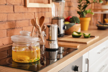 Modern electric stove with cooking pot and coffee maker in kitchen