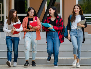 Group of four young attractive asian girls college students walking together in university campus talking and laughing with joy. Concept for education and college students life