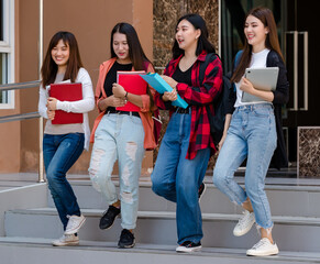 Group of four young attractive asian girls college students walking together down the stairs in university campus talking and laughing with joy. Concept for education and college students life