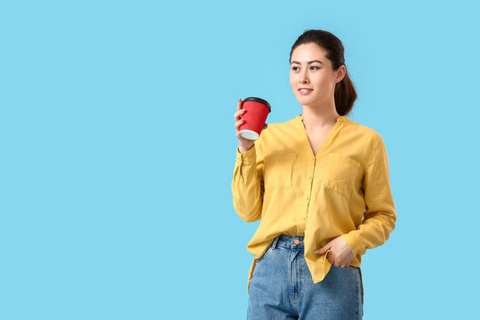 Beautiful young woman with coffee cup on color background