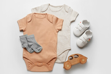 Set of baby clothes and toy on color background