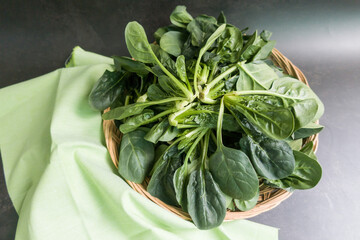 Fresh spinach leaves in a wooden plate.