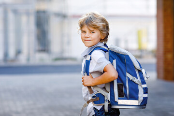 Happy little kid boy with backpack or satchel called Ranzen in German. Schoolkid on way to school....