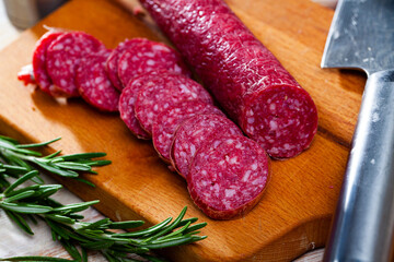 Traditional Catalan thin dry cured pork sausage Fuet Nobleza with sliced pieces on wooden background