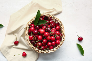 Wicker bowl with tasty ripe cherry on light background