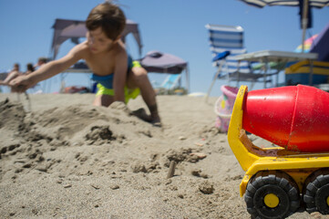 Fototapeta na wymiar Little boy playing with sand and beach toys