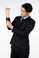 Portrait shot of Asian young healthy black short hair handsome white collar office worker in formal suit standing smiling adjusting button on sleeve in front of white background