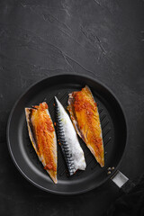 Marinated mackerel on grill pan on black background, top view with copy space