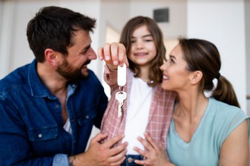 Portrait of smiling caucasian family with daughter holding keys of their new home.