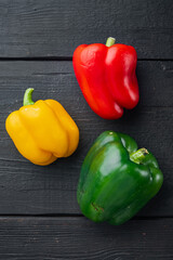 Green , yellow and red bell pepper, on black wooden table background, top view flat lay