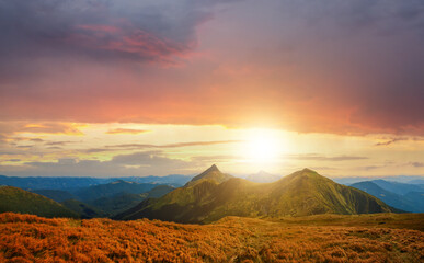 Fototapeta premium Sunset landscape of high mountain peaks under vibrant colorful evening sky.