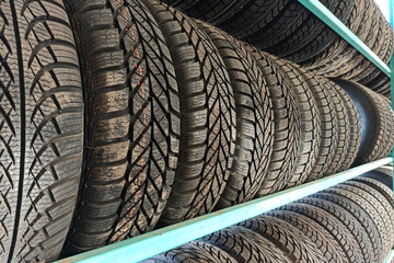 Many black rubber car tires on store shelf for sale.