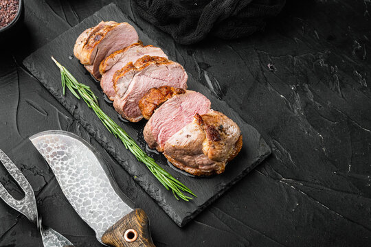 Juicy duck breast steaks, on stone serving board, on black stone background, with copyspace  and space for text