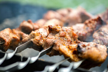 Shashlik or shish kebab preparing on barbecue grill over hot charcoal. Grilled pieces of pork meat on metal skewers.