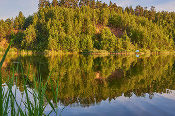  Hills covered with forest are reflected in the surface of the lake.