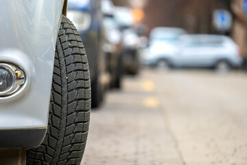 Closeup of parked car on a city street side with new winter rubber tires.