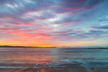 Fototapeta na wymiar Cloud covered sunrise seascape tinged with pink
