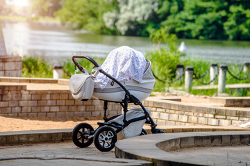 A baby stroller is standing in a summer park