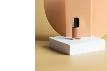 Modern nail care and beauty concept. Beige nail polish on the podium  at white beige background.