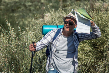 mature tourist man with backpack and map hiking or trekking up the mountain