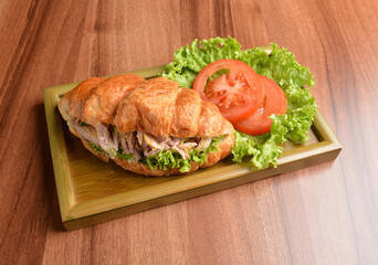 fried chicken or tuna fish with sesame sauce in baked crispy croissant bread and vegetables salad on wood table fresh halal pastry sandwich menu